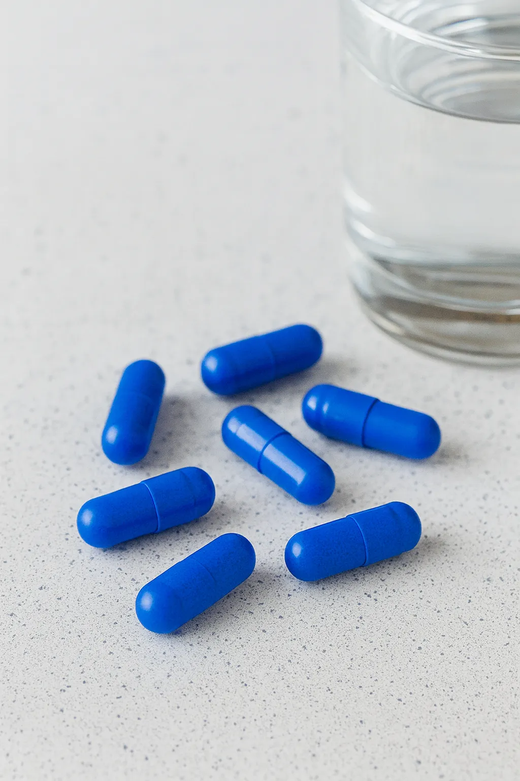 Cápsulas azuis e copo d'água